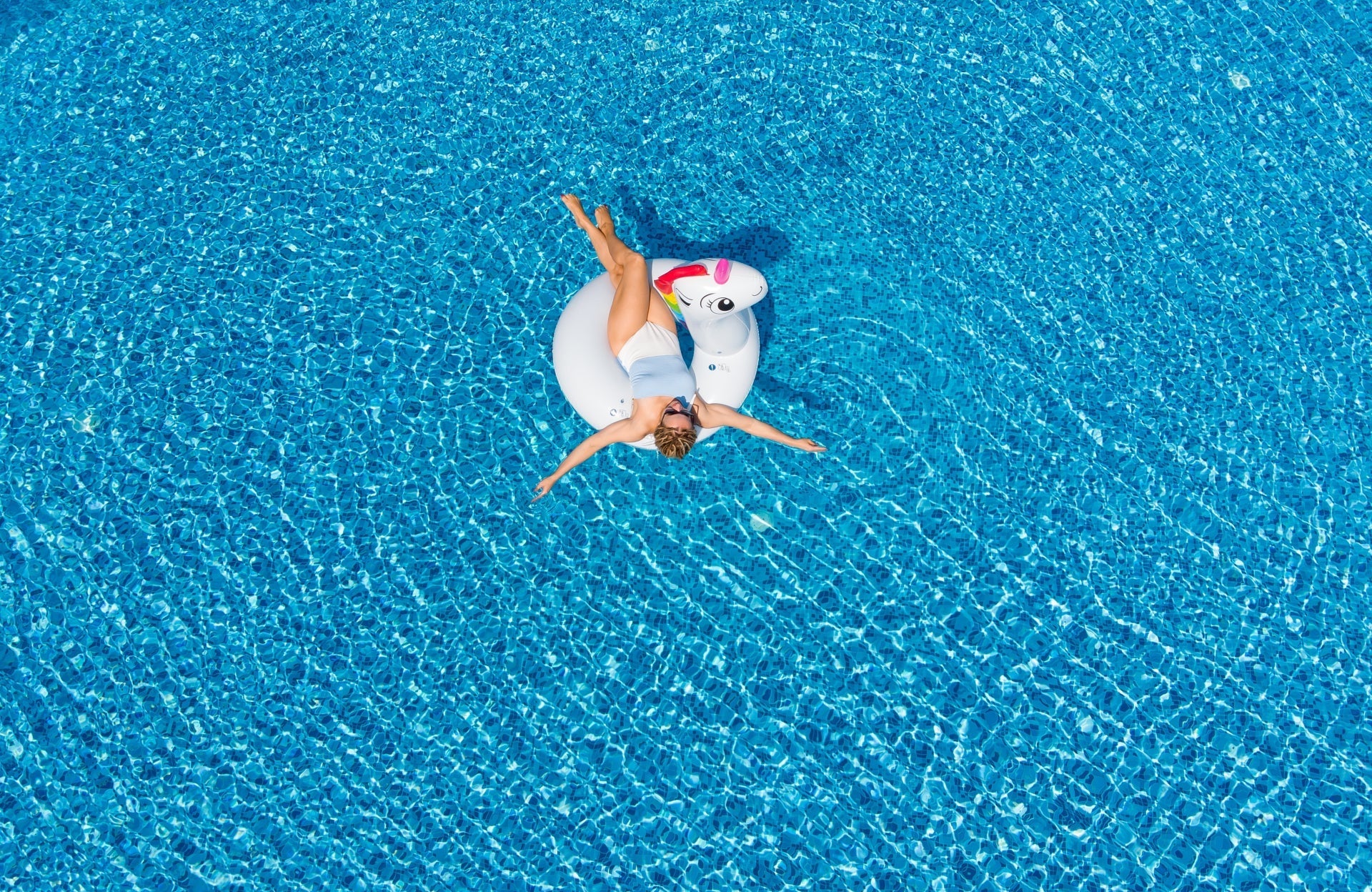 Woman relaxing on a unicorn float in a swimming pool