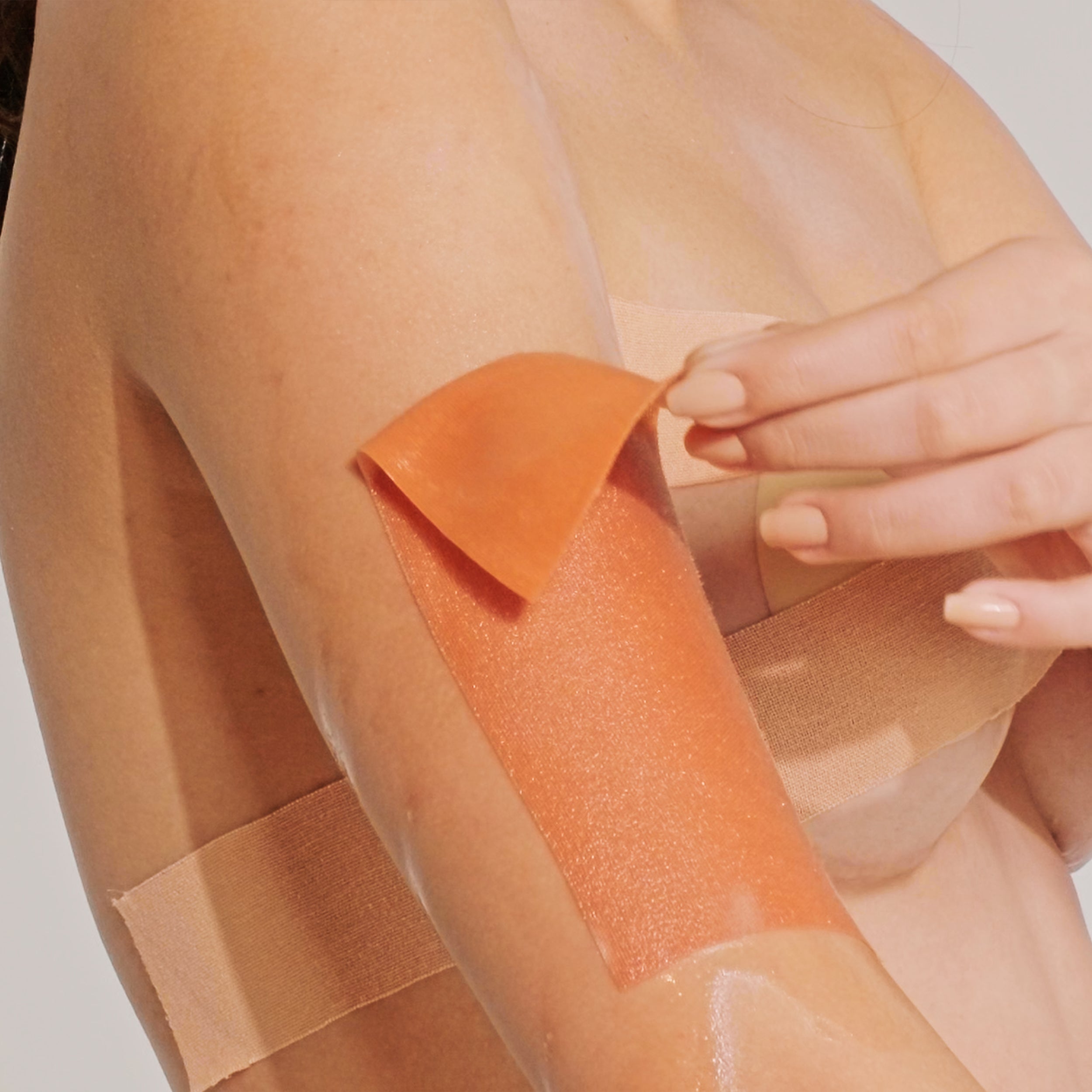 Model gently peeling off one edge of the body tape, which naturally comes loose, for easy removal