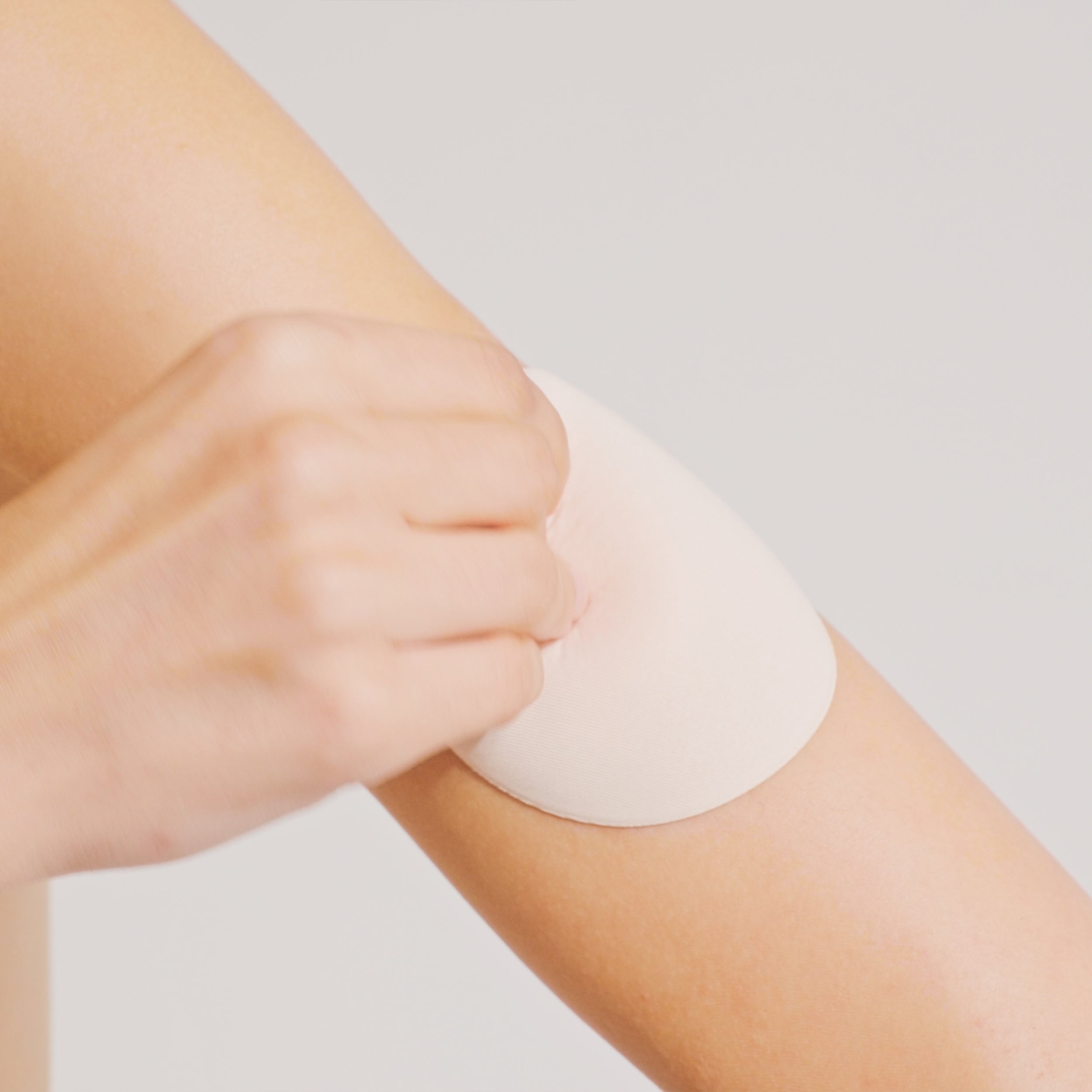 Model carefully lifting one edge of the Nippetals MicroBra fabric nipple cover for gentle removal