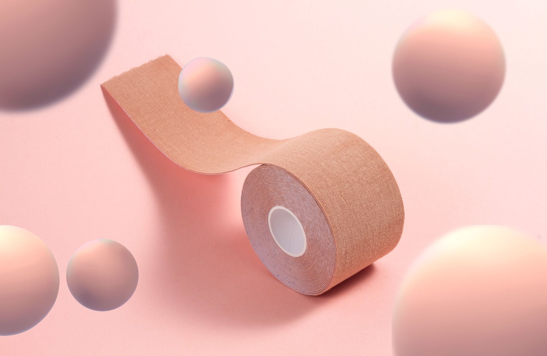 A roll of Nippetals boob tape, displayed on a soft pink background, highlighting its innovative design for discreet support