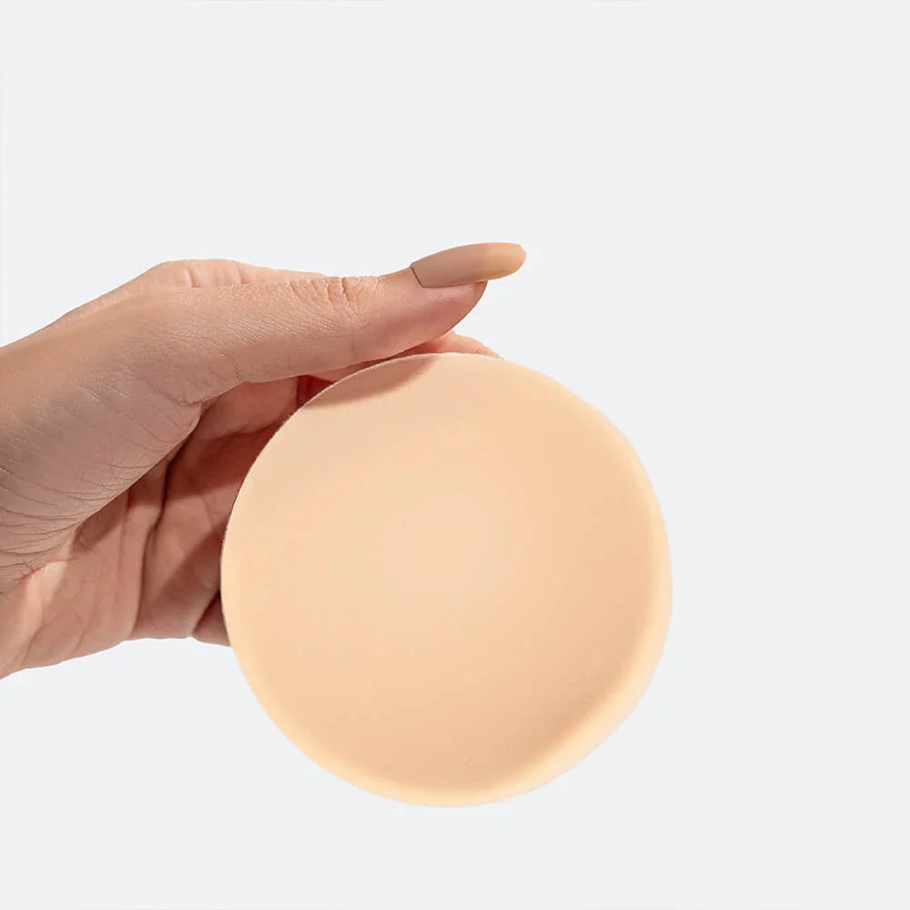 A hand holding a Nippetals non-adhesive nipple cover for seamless and reusable coverage. Ideal for sensitive skin