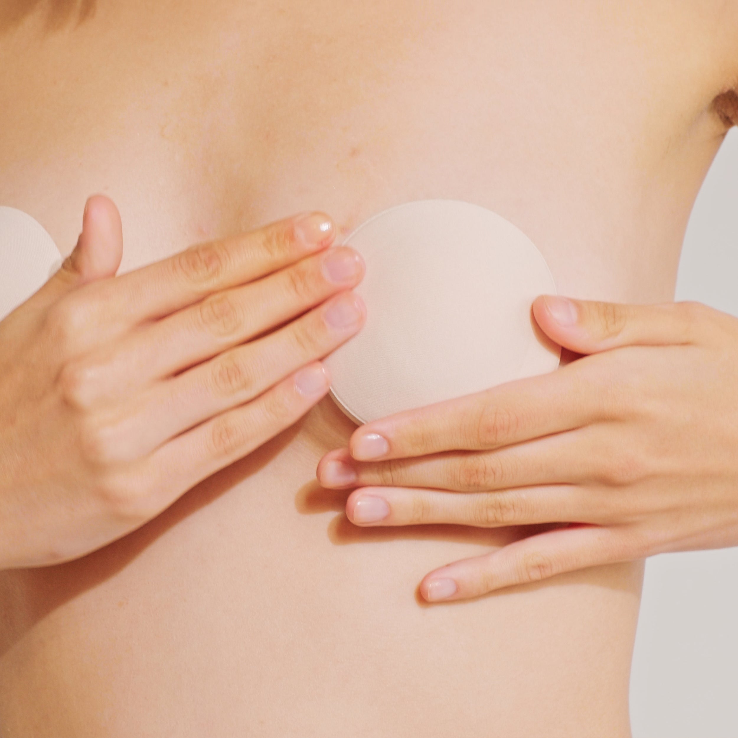 Model pressing down the Nippetals MicroBra fabric nipple cover firmly, smoothing out any bubbles for a seamless fit