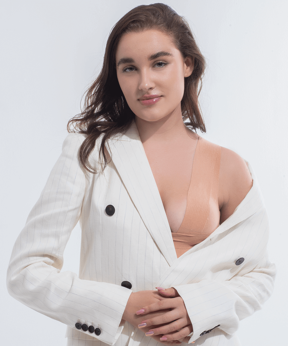 Model wearing a blazer with boob tape visible on one side for discreet support and a subtle finish
